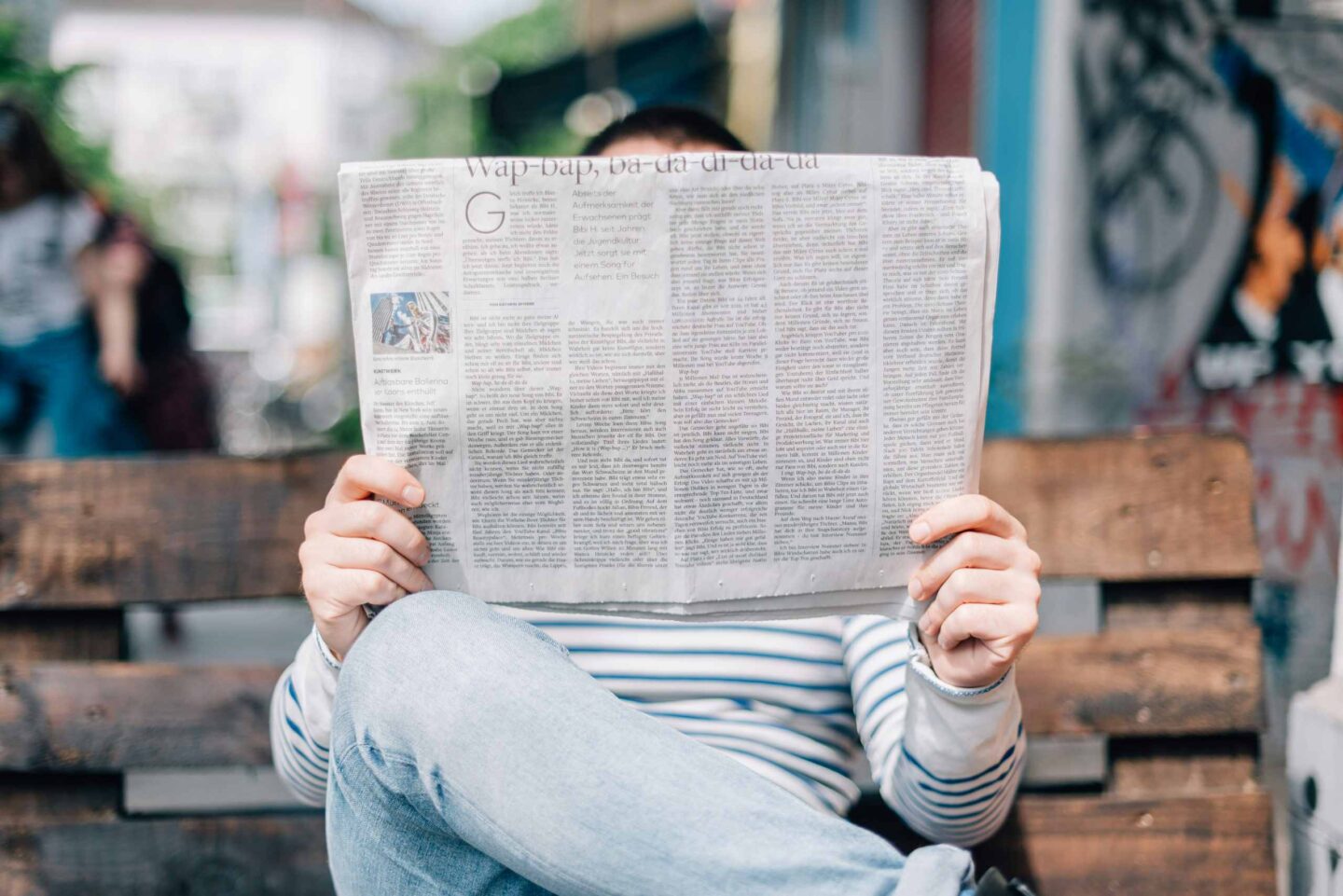 Mann ließt eine Zeitung auf einer Sitzbank